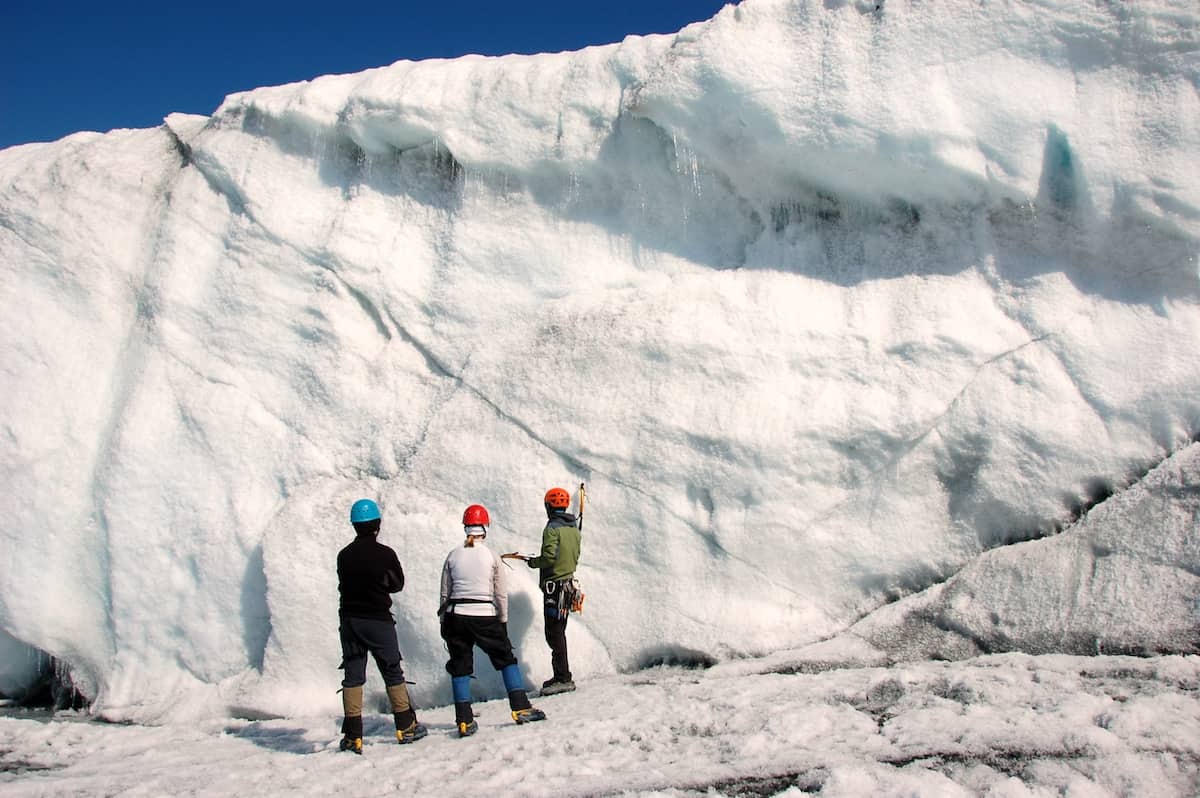 two men and one woman preparing to climb glacier wall
