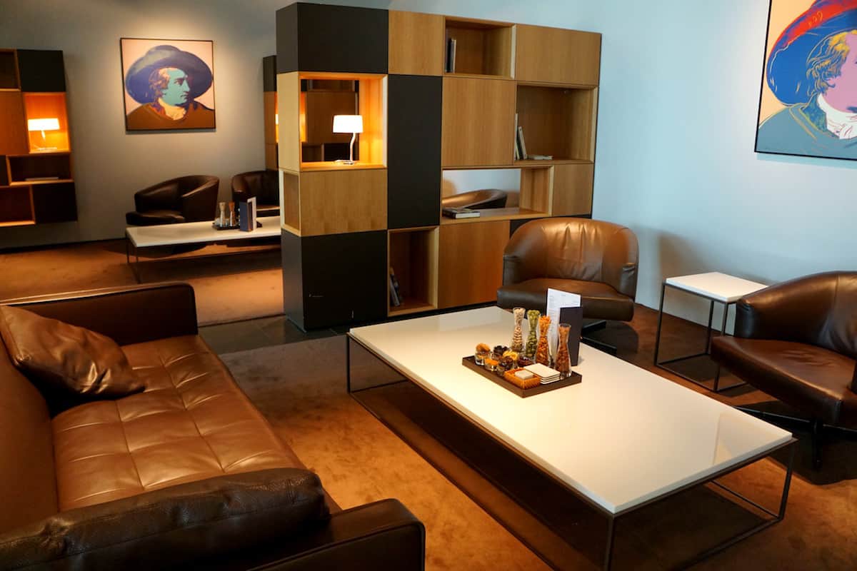 brown leather chairs and couch, wooden bookcase in airport lounge