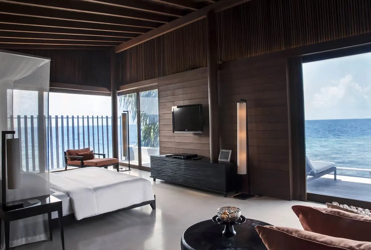 Bed and living area of Park Hyatt Maldives Hadahaa overwater bungalow.