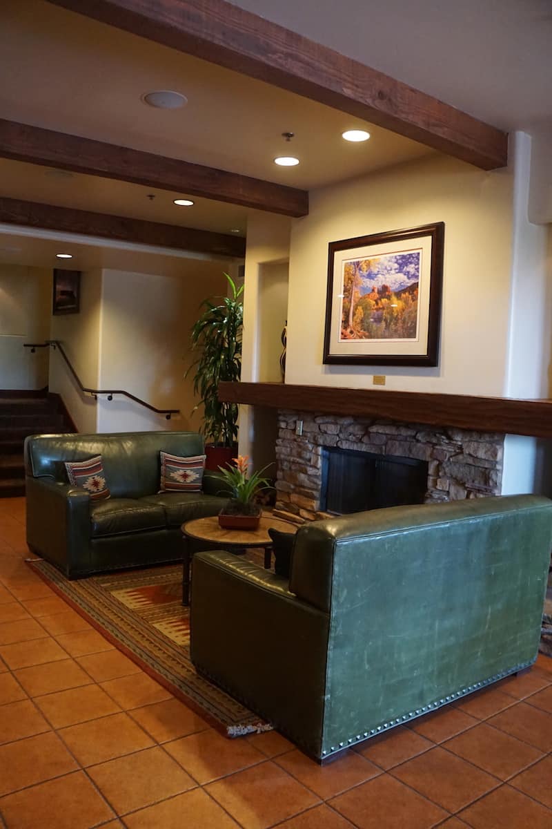 Two green leather loveseats flank a stone-faced fireplace.