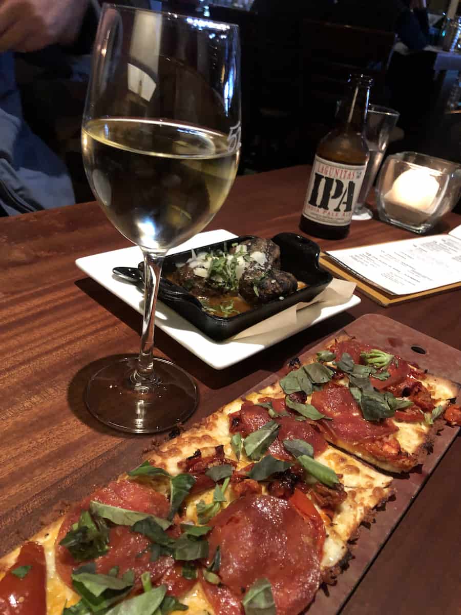 Pepperoni flatbread pizza, glass of white wine, meatballs, and IPA beer during Happy Hour at Seasons 52 South Coast Plaza, one of the best things to do in Costa Mesa 