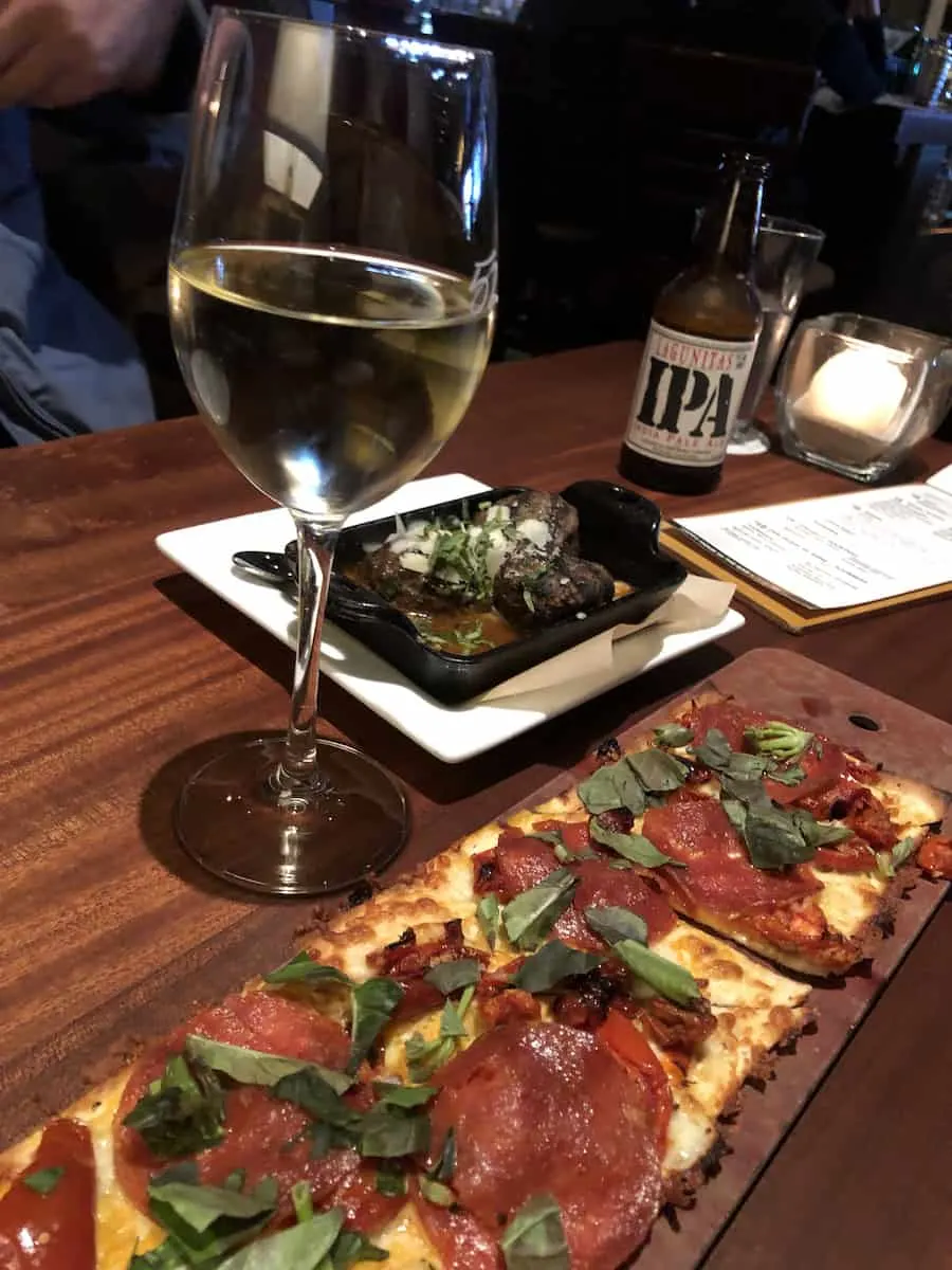 Pepperoni flatbread pizza, glass of white wine, meatballs, and IPA beer during Happy Hour at Seasons 52 South Coast Plaza, one of the best things to do in Costa Mesa