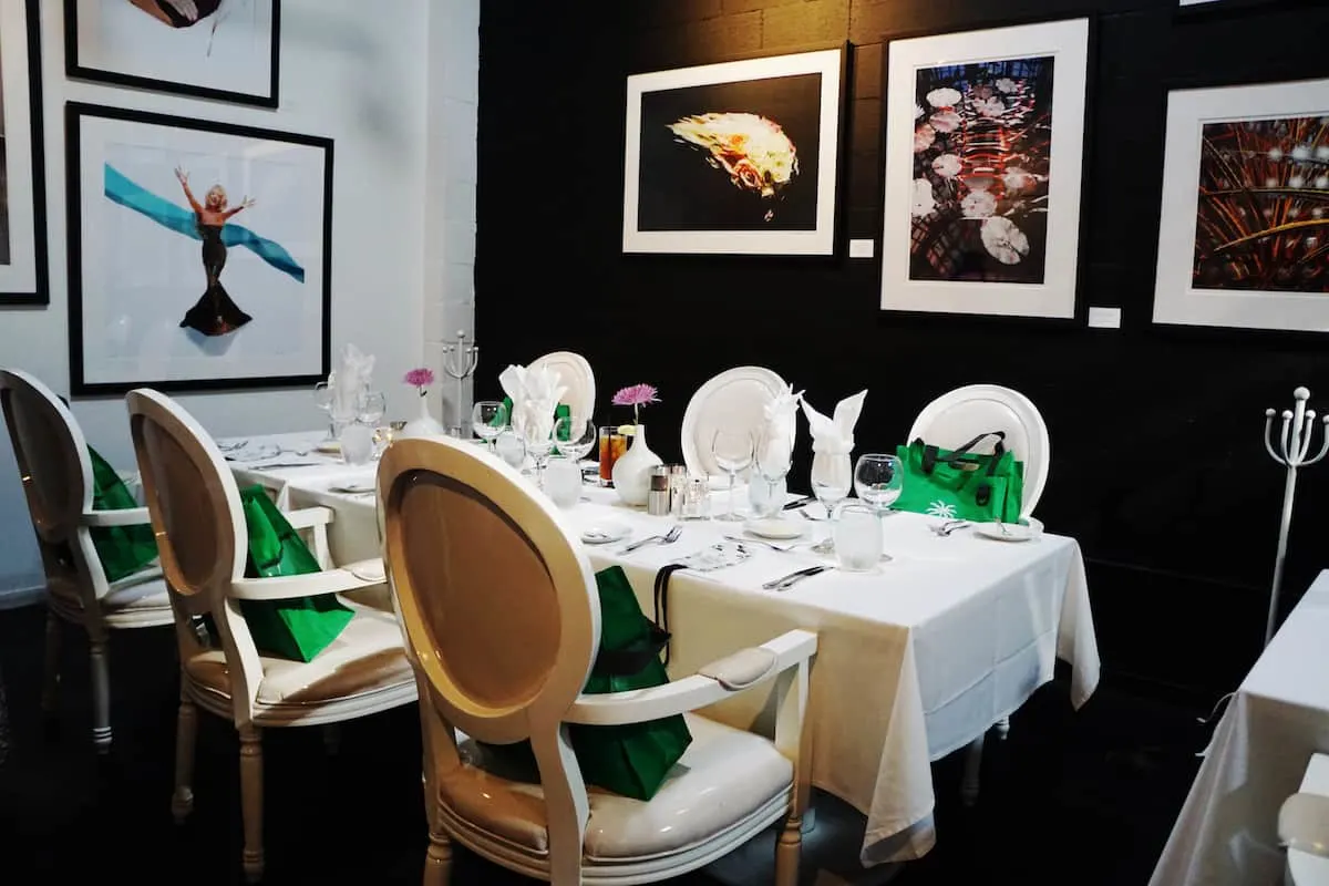 chic restaurant with white furniture black wall and celebrity photographs