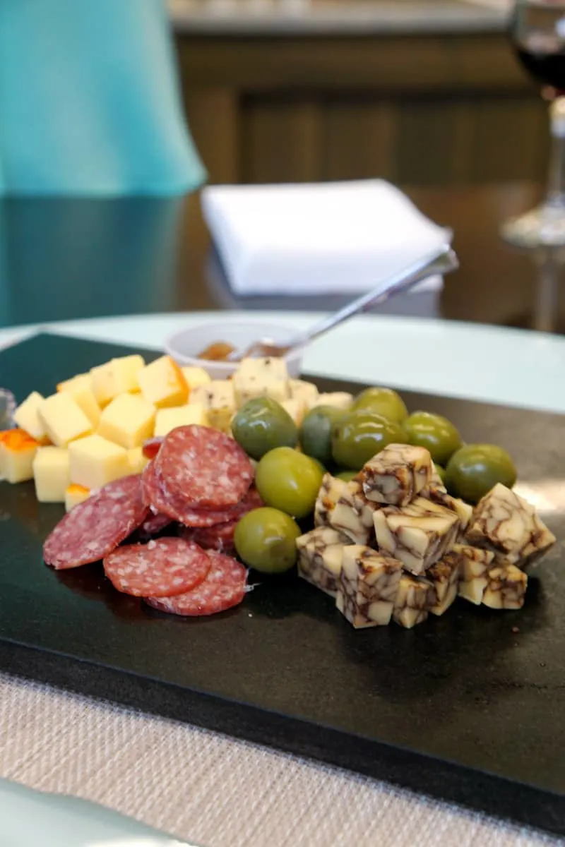 A charcuterie plate of two cheeses, salami, and olives at Twin Sisters Creamery. Looking for the best things to do in Lynden? Visit Twin Sisters Creamery and try over 7o types of cheese including Whatcom Blue. #cheese #charcuterie #thingstodoinLynden #Lynden #Washington
