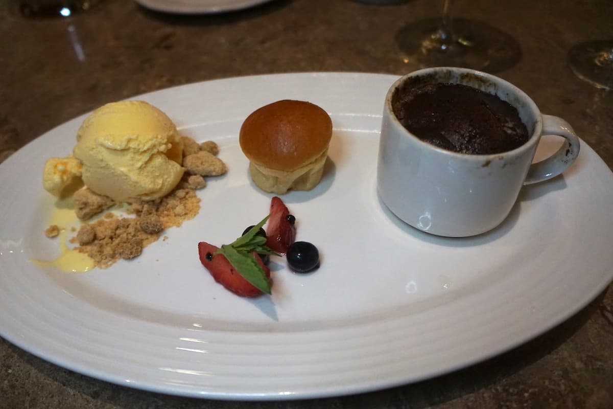 vanilla ice cream, muffin, cup of chocolate souffle on white plate