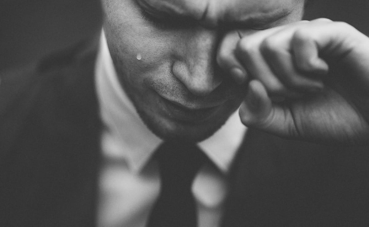 man in black suit wiping his tears