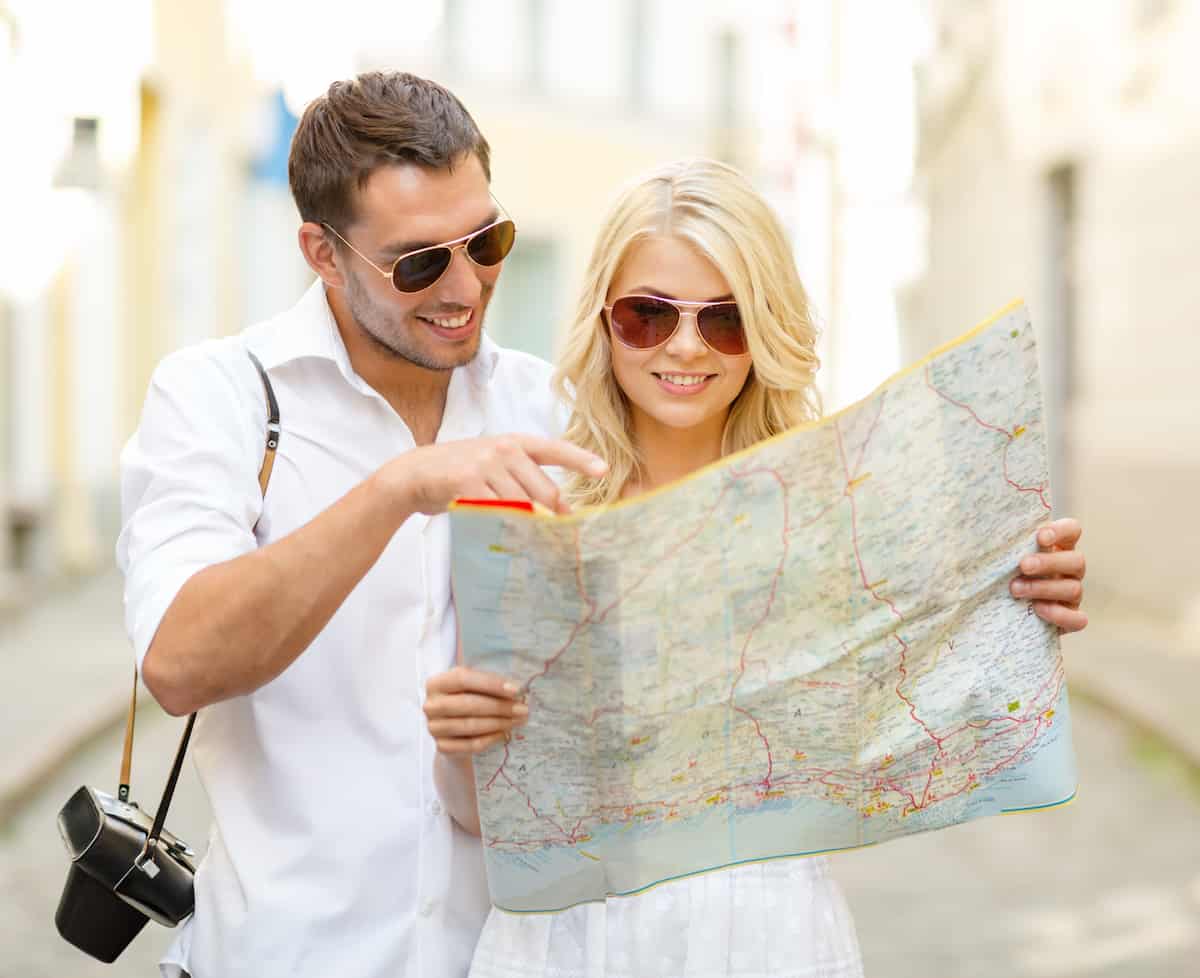 smiling couple in sunglasses with map in the city