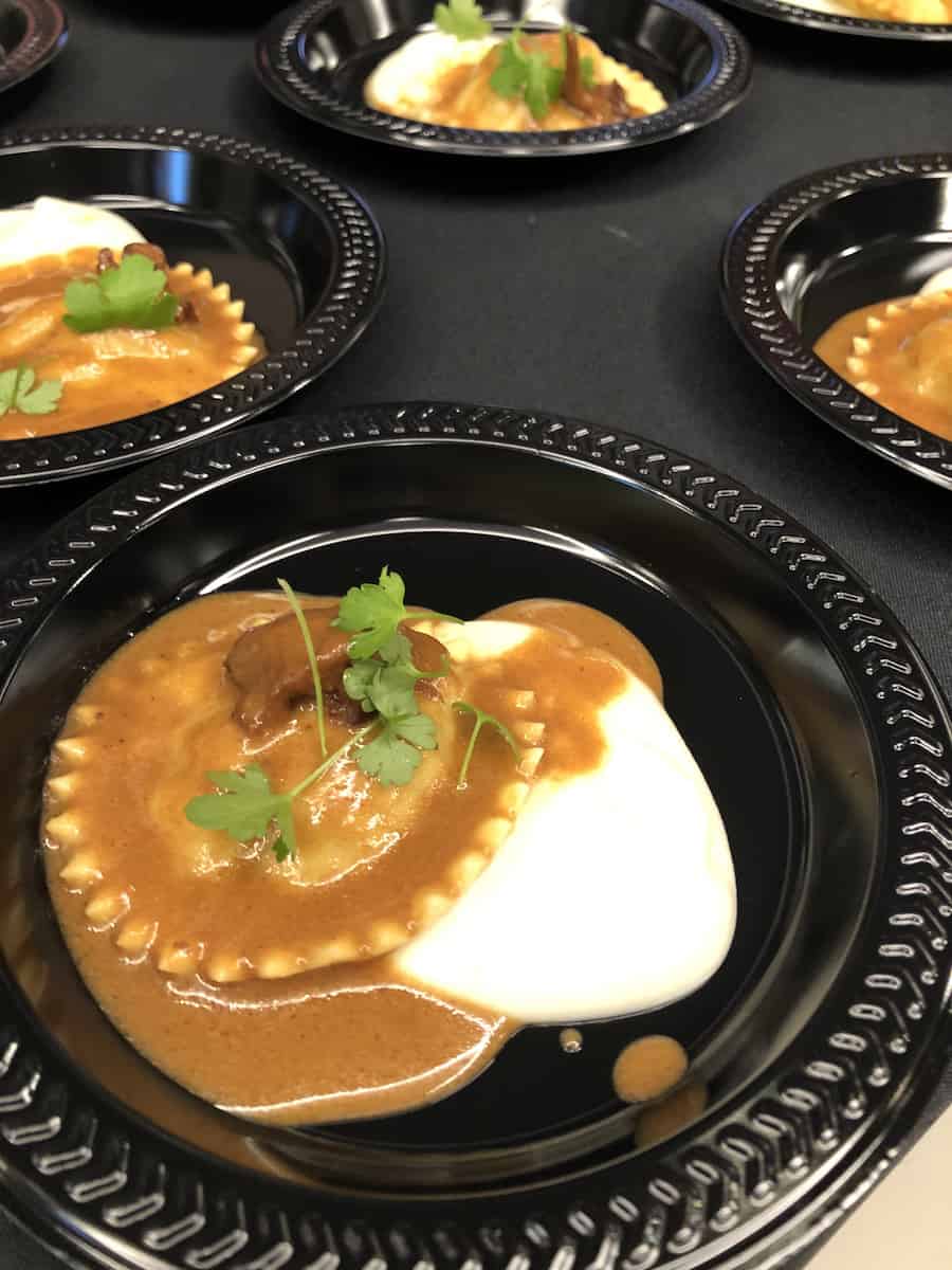 ravioli topped with brown and white sauce on black plate