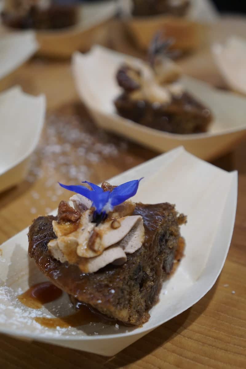 small slice of brown pudding cake topped with mousse and purple flower