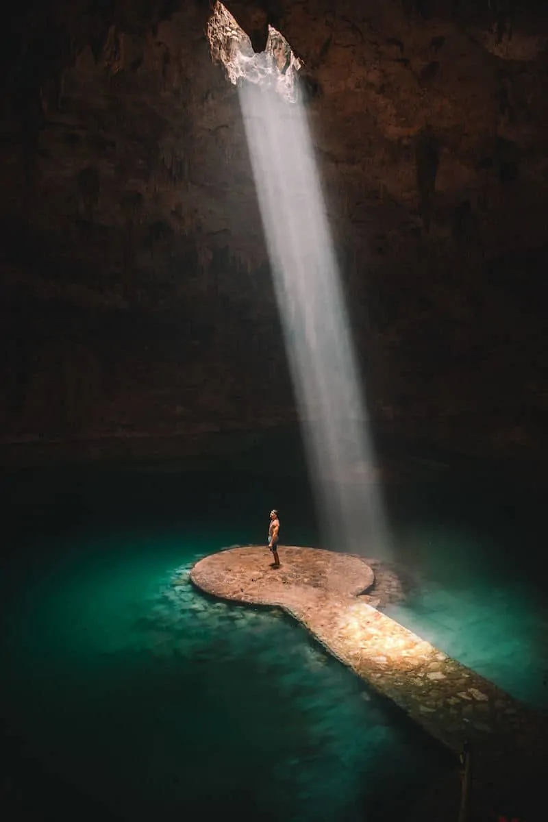 man standing in xenote cave in tulum