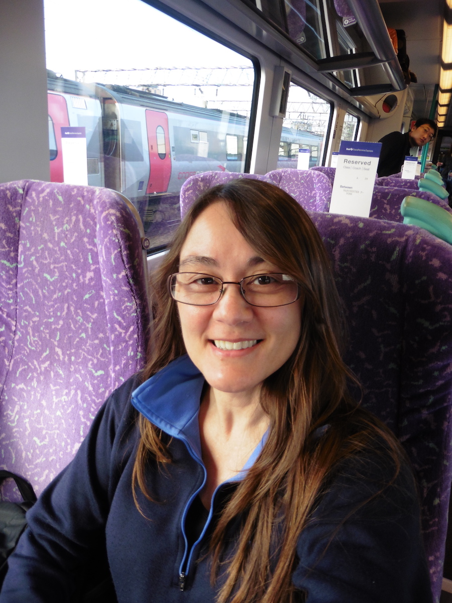 woman with brown hair and glasses riding purple chaired train, Debra Schroeder taking train from Manchester to Edinburgh in coach