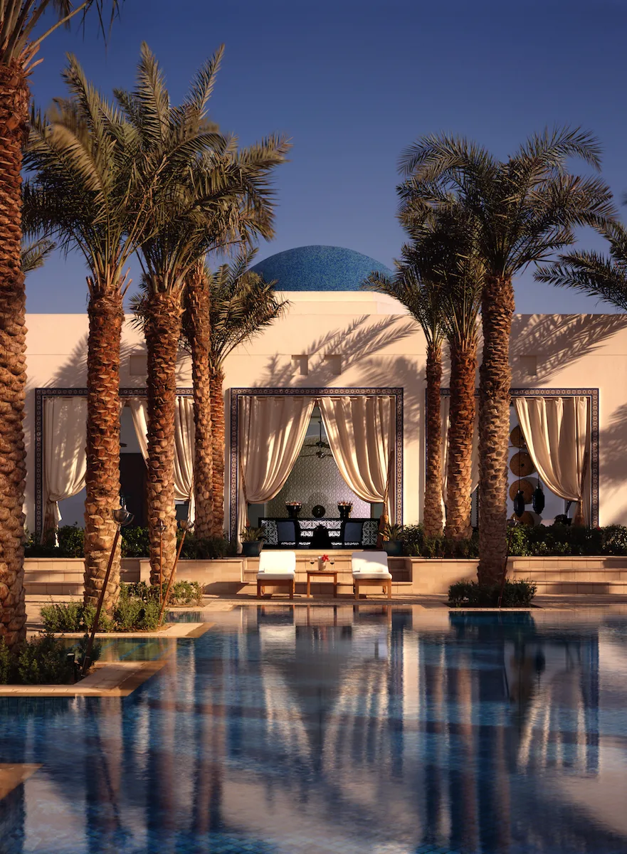 pool chairs and cabana by palm tree lined pool at Park Hyatt Dubai