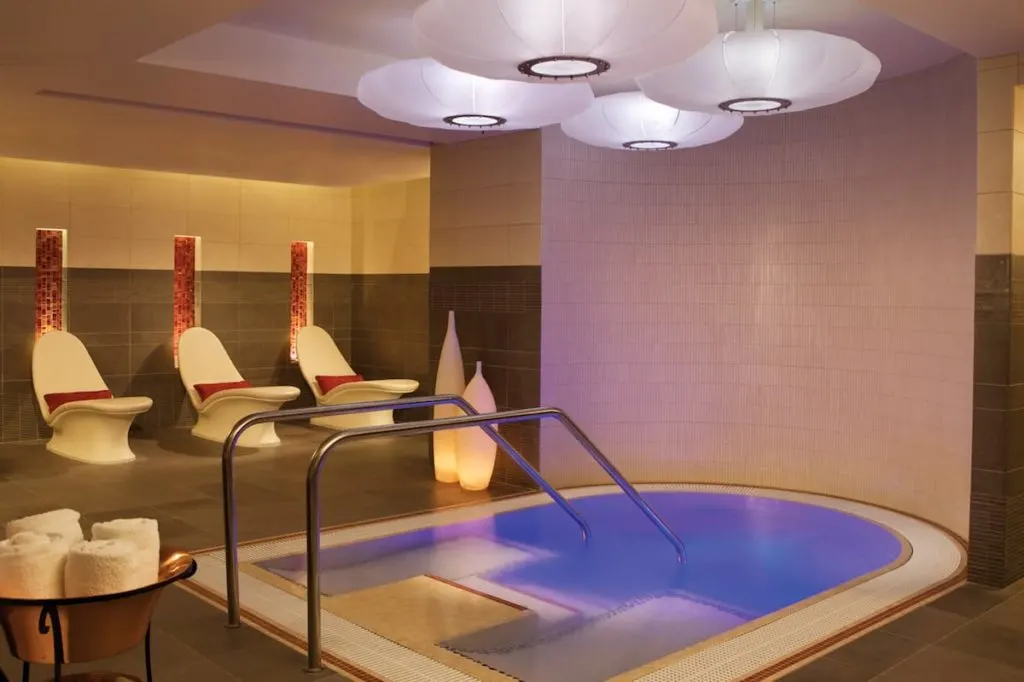 three white lounge chairs next to a medium sized step down jacuzzi at Canyon Ranch Spa Las Vegas