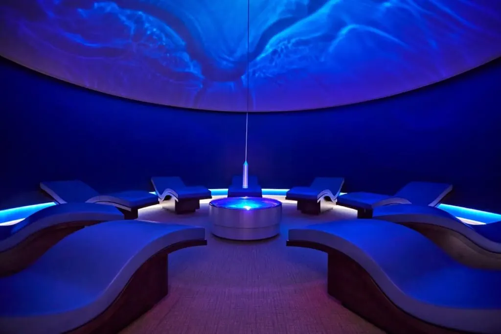 nine s-shaped lounge chairs in a domed blue-tinted relaxation room at Canyon Ranch Spa Las Vegas where waves are projected on the ceiling