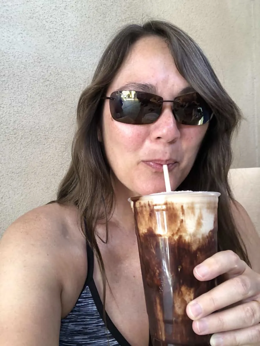 girl wearing sunglasses sipping chocolate drink