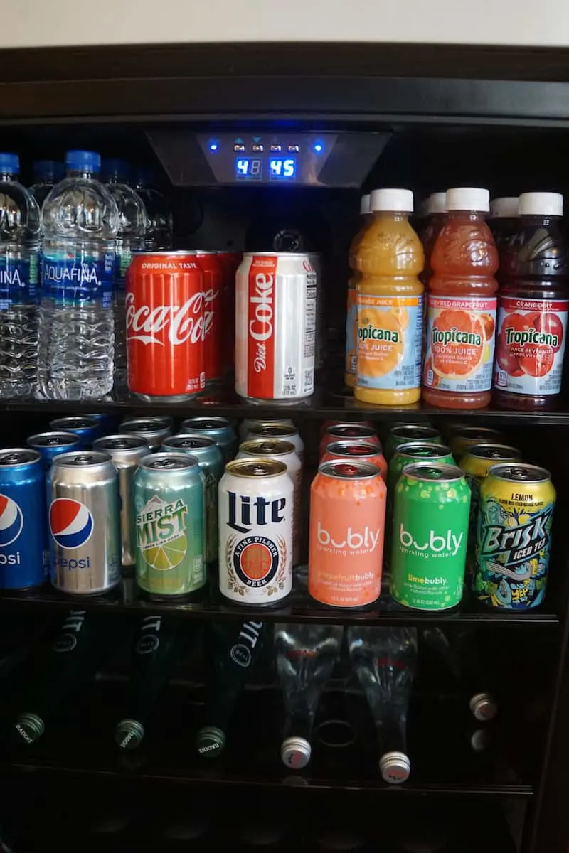 beverage fridge stocked with water, sodas, juices, ice tea, and beer