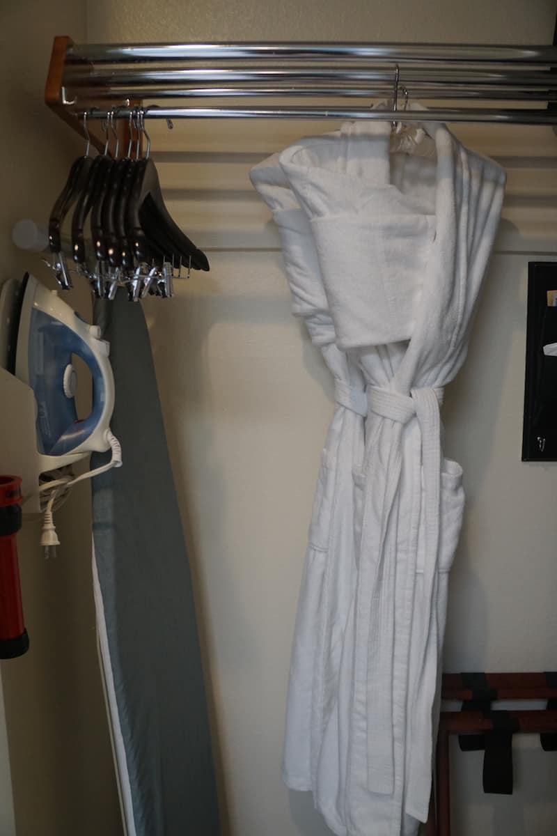 closet with iron, ironing board, and two white robes