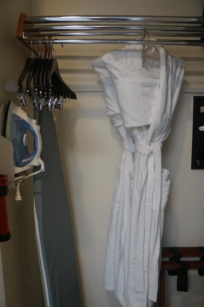 closet with iron, ironing board, and two white robes