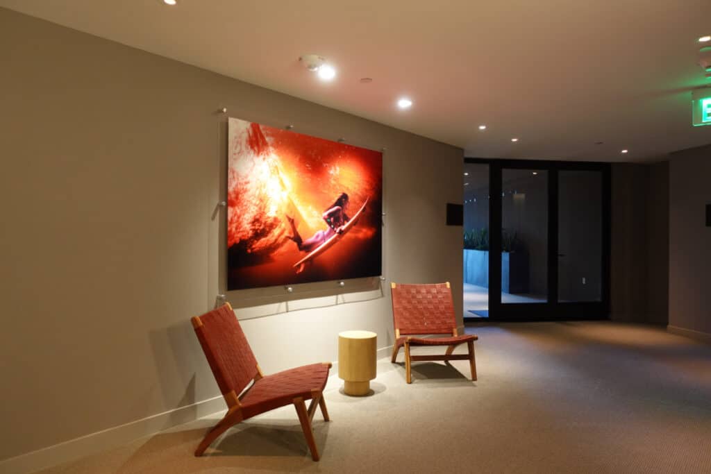 two woven leather chairs below surfer girl photo in hotel hallway 