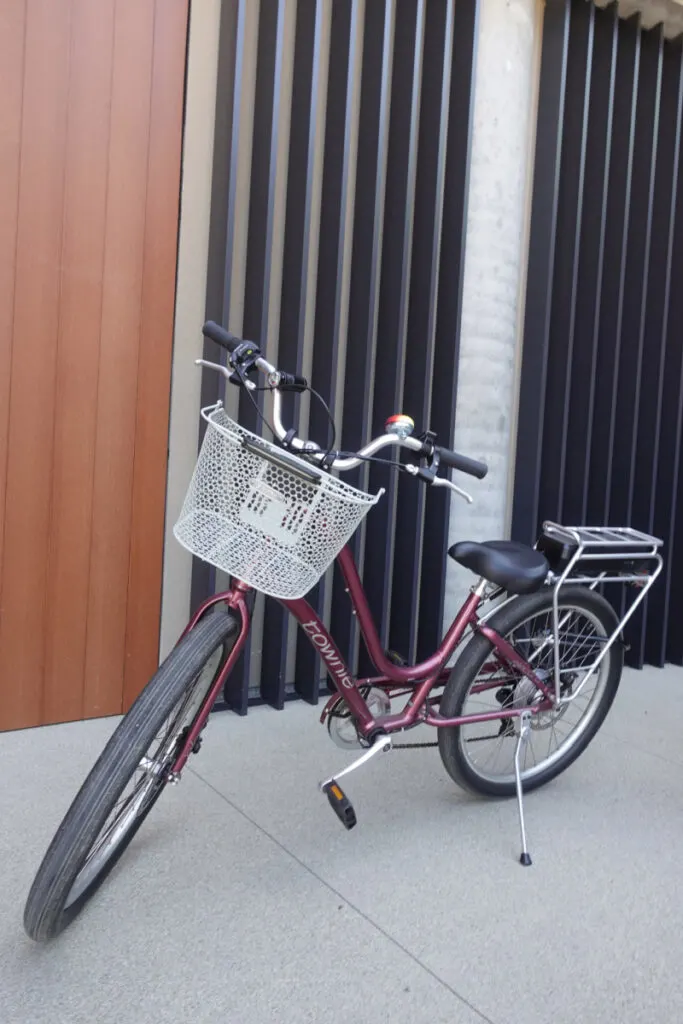 burgundy electric bicycle with white basket on handle bars