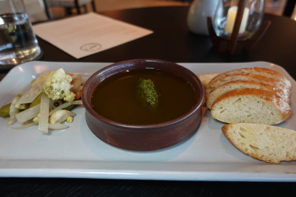 olive oil based dip with slices of sourdough bread and picked vegetables