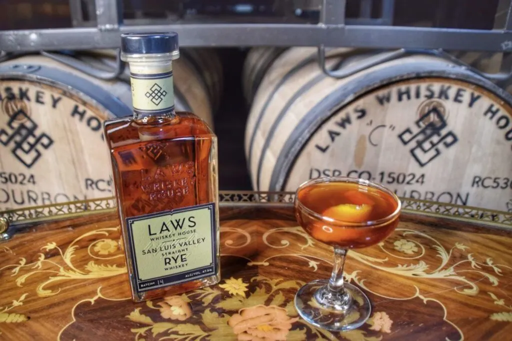 whiskey cocktail on decorative tray in front of bourbon barrels on world whiskey day