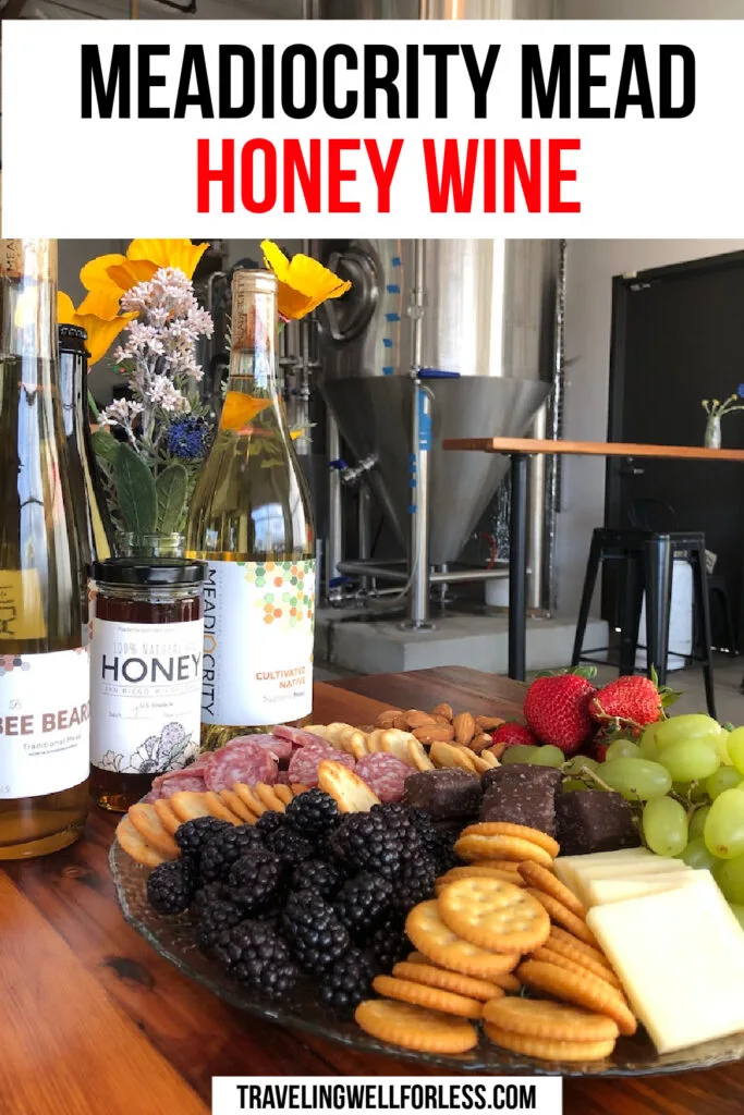 bottles of mead and honey with plate of meat, cheese, crackers, and fruit in meadery
