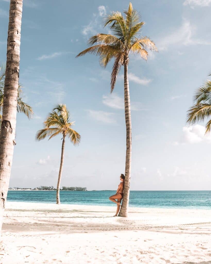 woman leaning on tree near beach, nassau bahamas caribean