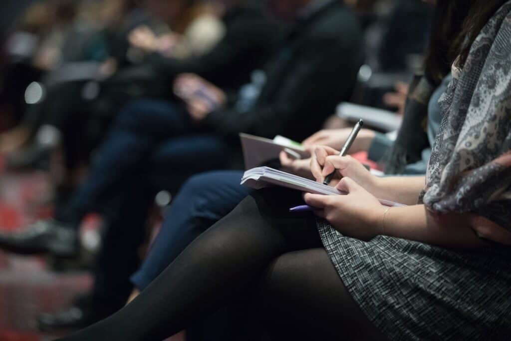 people sitting on chairs while writing on notebooks; earn miles and points without a credit card with plan a meeting or event