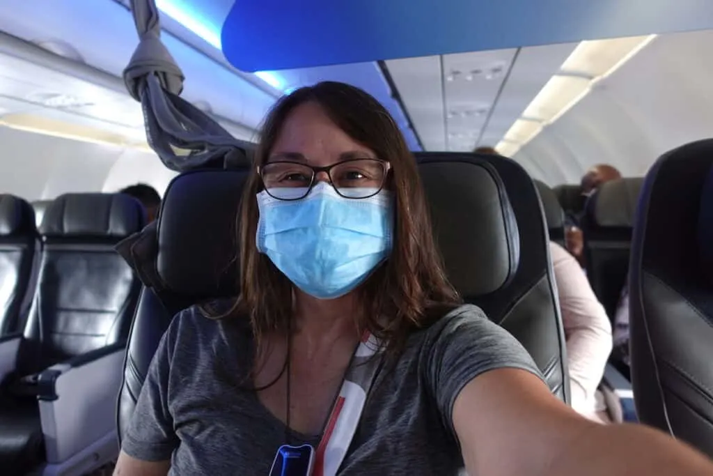 woman with long brown hair wearing glasses and face mask in first class cabin on airplane alaska airlines first class los angeles to puerto vallarta