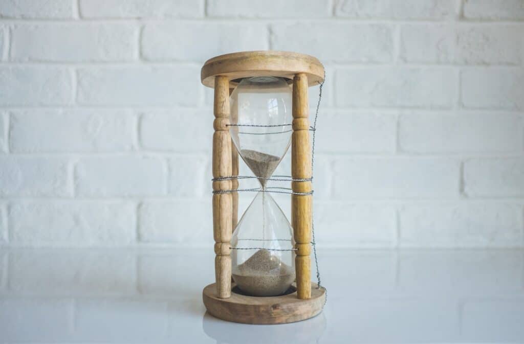 brown sand running out in clear hourglass with brown frame