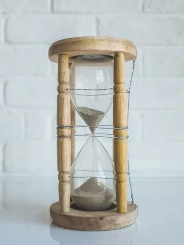 brown sand running out in clear hourglass with brown frame