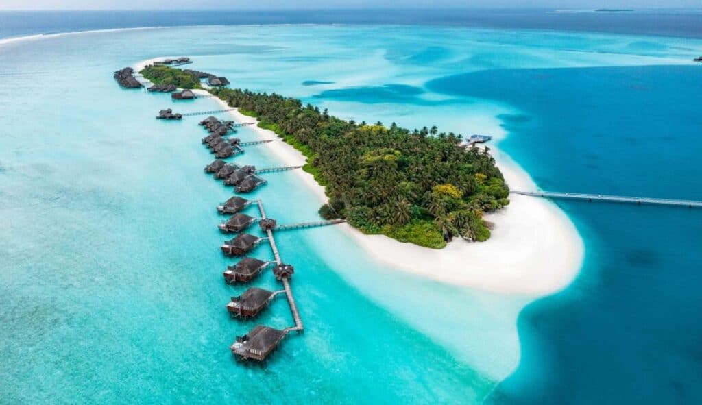 lush green tropical island with overwater villas surrounded by turquoise green and azure blue water