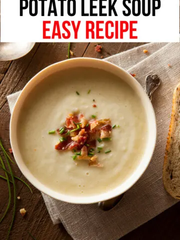 white bowl of creamy beige soup topped with bacon on top of light brown linen tablecloth on wood table