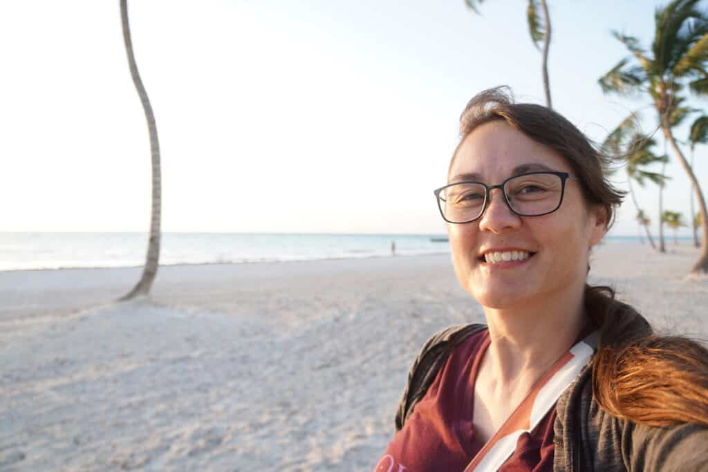 smiling brown haired girl with glasses on white sand beach in the tropics. Debra Schroeder at Hyatt Zilara Cap Cana