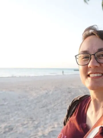 smiling brown haired girl with glasses on white sand beach in the tropics. Debra Schroeder at Hyatt Zilara Cap Cana