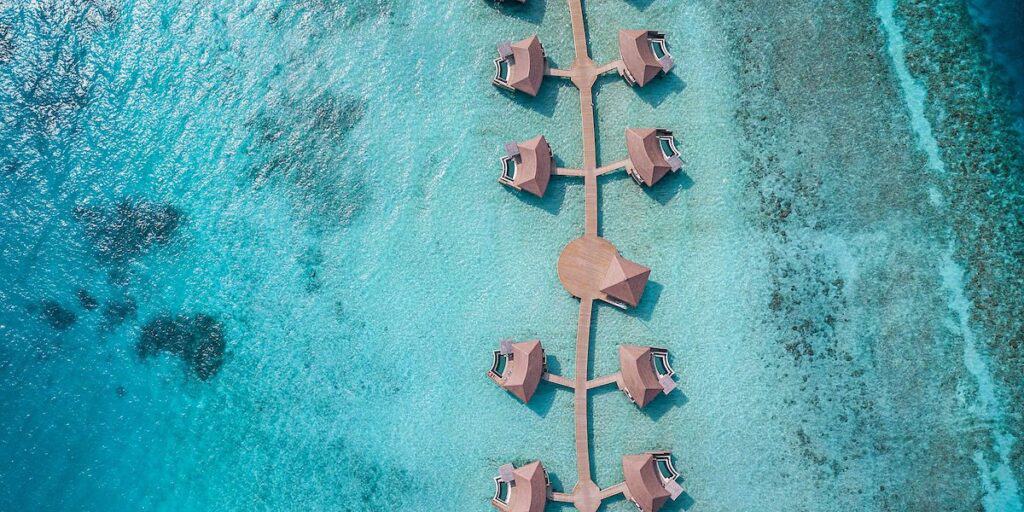 brown overwater bungalos villas in turquoise green water