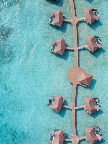 brown overwater bungalos villas in turquoise green water