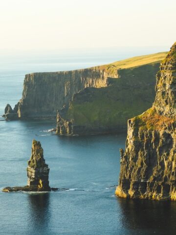 rock formation beside sea under white sky, cliffs of moher, ireland