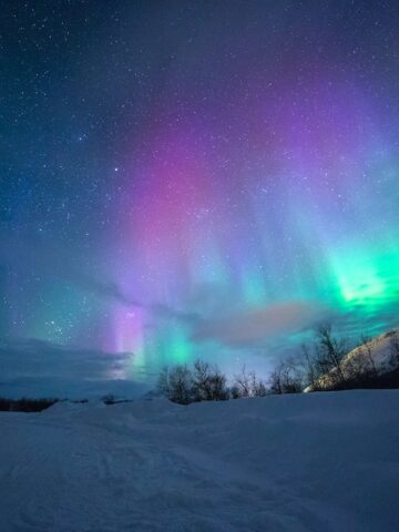 northern lights over snow capped mountains in Norway