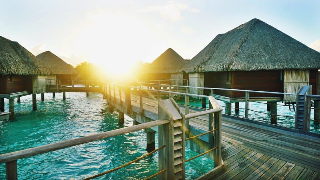 brown wooden dock between houses, overwater bungalow villas in french polynesia