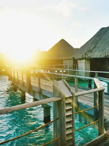 brown wooden dock between houses, overwater bungalow villas in french polynesia