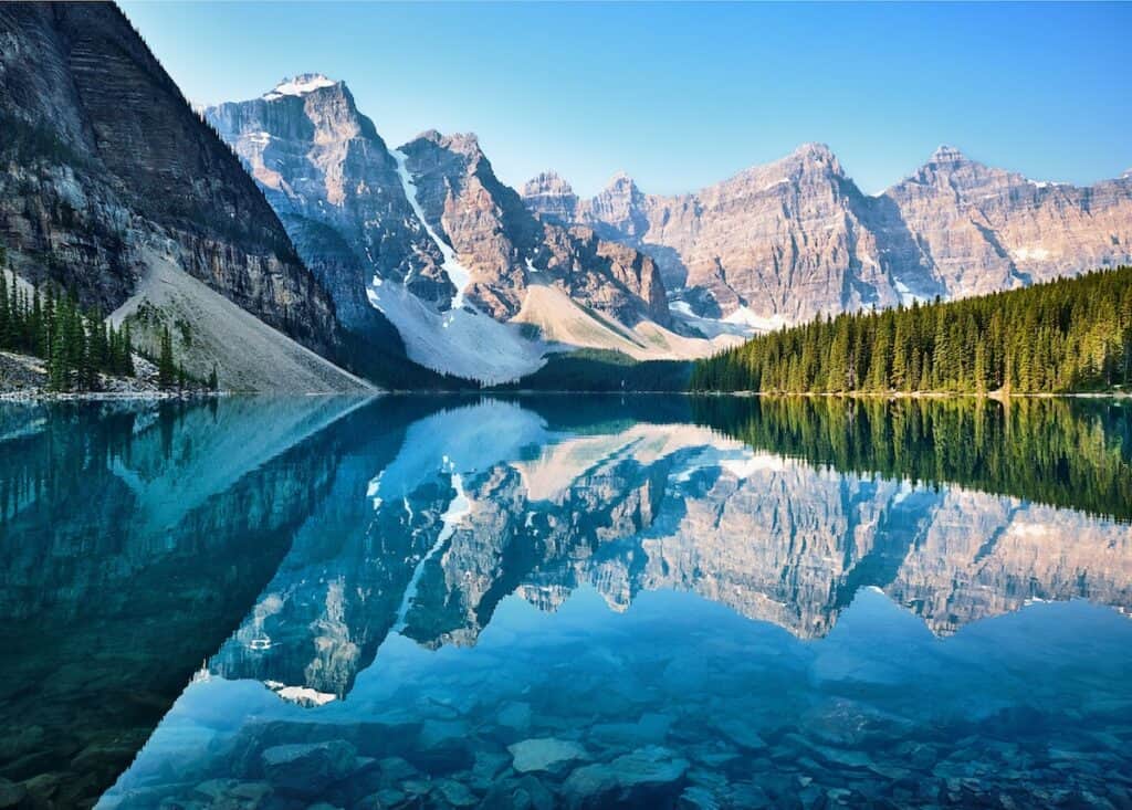 snow covered mountains and tall dark green trees reflected in crystal clear lake, scenery of mountain, Moraine Lake, Banff, Canada