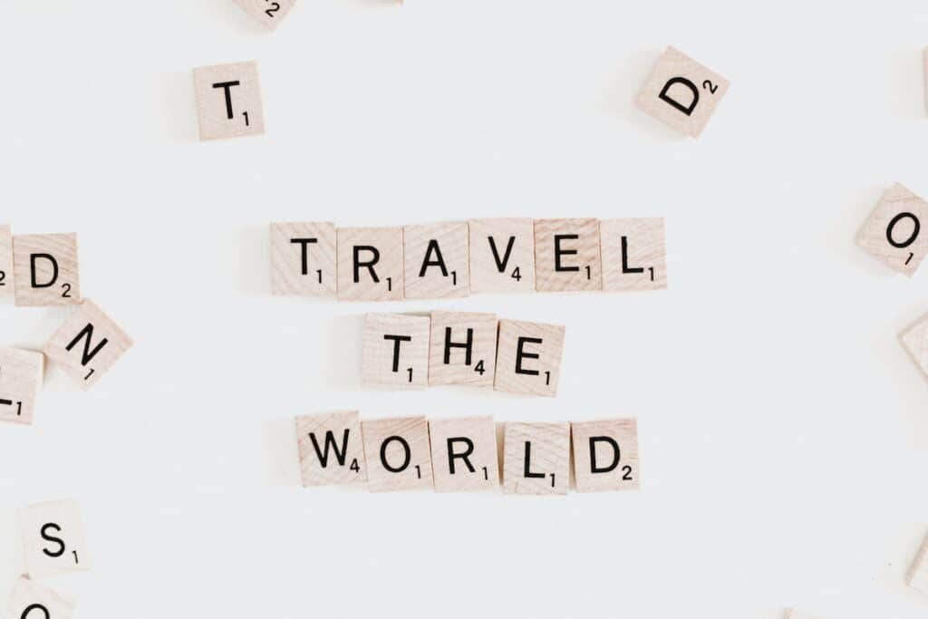 baldosas de madera de color claro con letras que explican la foto de viajar por el mundo, baldosas de scrabble viajan por el mundo