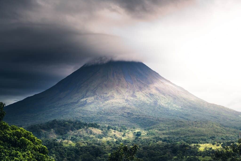 a very tall mountain with a very cloudy sky above it, 