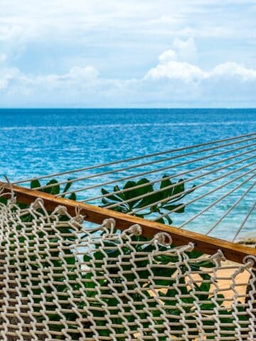 white hammock tied on tree on beach overlooking crystal blue water Malolo Island Fiji