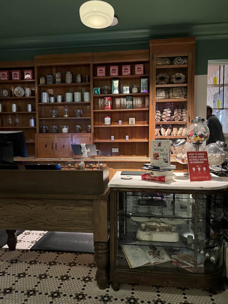 red and white tin containers and loaves of thick brown bread on brown shelves at fake bakery