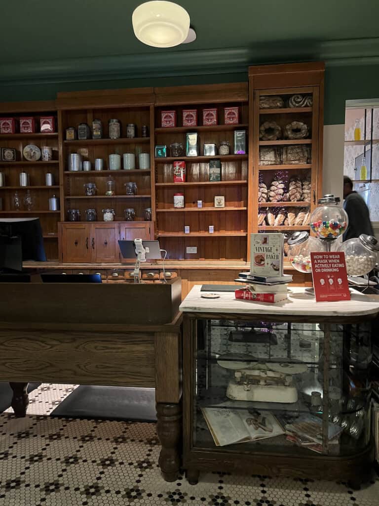 red and white tin containers and loaves of thick brown bread on brown shelves at fake bakery