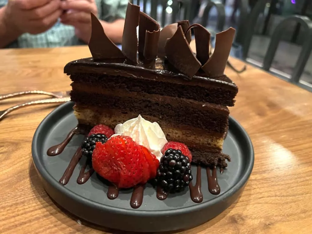 Devil's Food and banana bread cake topped with large chocolate shards with berries on black round plate