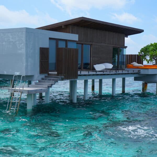 gray and brown building on stilts over turquoise blue water, overwater villa suite in Maldives